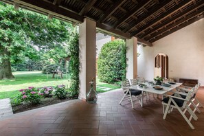 Une terrasse extérieure avec une table et des chaises, entourée de verdure et offrant une vue sur un jardin.