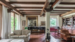 A spacious living room with a piano, a fireplace, and a large bookshelf. - Beautiful villa with pool surrounded by nature near Golf and Tennis courts (Beregazzo con Figliaro (Co))