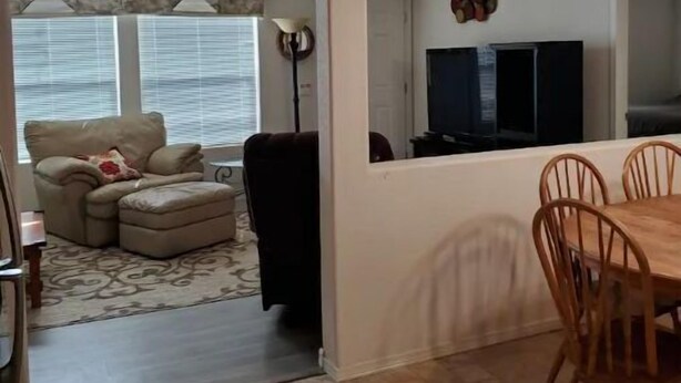 Un salon comprenant un canapé, un pouf et un coin repas avec une table et des chaises.