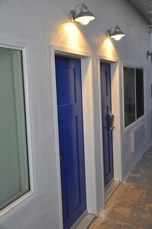 A building with three blue doors and two wall-mounted lights. - The Belmont Shore Inn (Long Beach)