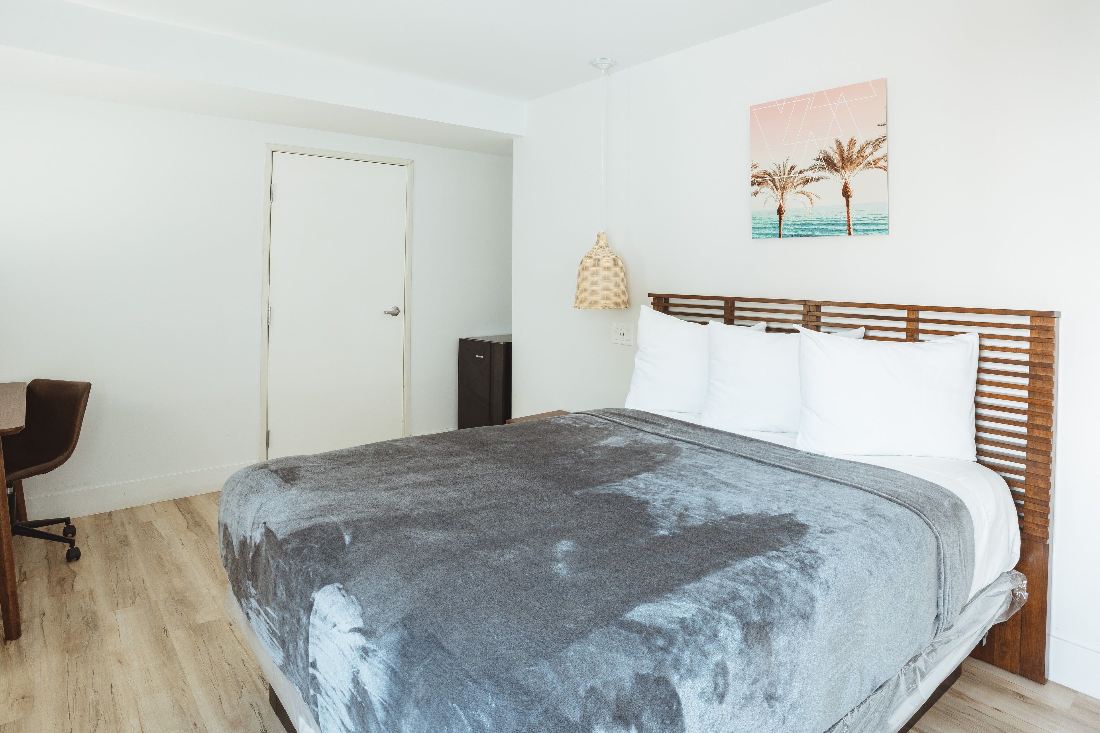 A bedroom with a bed, a desk, and a chair.