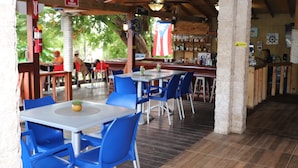 Un restaurante al aire libre con mesas, sillas, una zona de bar y una bandera.