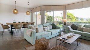 A modern living room with a sofa, coffee table, and dining area.