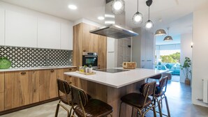 A modern kitchen with a central island, wooden cabinetry, and pendant lighting.