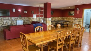 A dining area with a wooden table and chairs, a red sofa, and a stone wall.