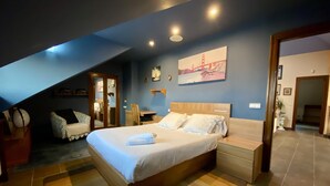 A bedroom with a large bed, a desk, and a chair. There is a painting on the wall and a door leading to another room. - Finca Canal, Rural Villa in the Comarca de la Sidra (Quintueles)