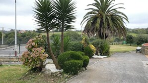 A paved pathway with palm trees and shrubs, a fence, and a distant view of houses and hills. - Finca Canal, Rural Villa in the Comarca de la Sidra (Quintueles)