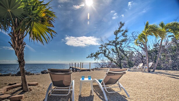 Un espace aménagé avec deux chaises et une table, situé au bord de la plage et offrant une vue sur la mer.