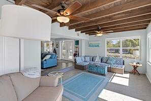 Relax in this spacious living area with a high ceiling, ceiling fans, and a large window offering a view of the outdoors.