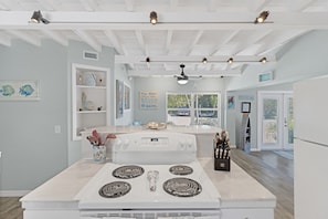Modern kitchen with central stove, four burners, and digital clock, featuring white cabinetry and countertops.