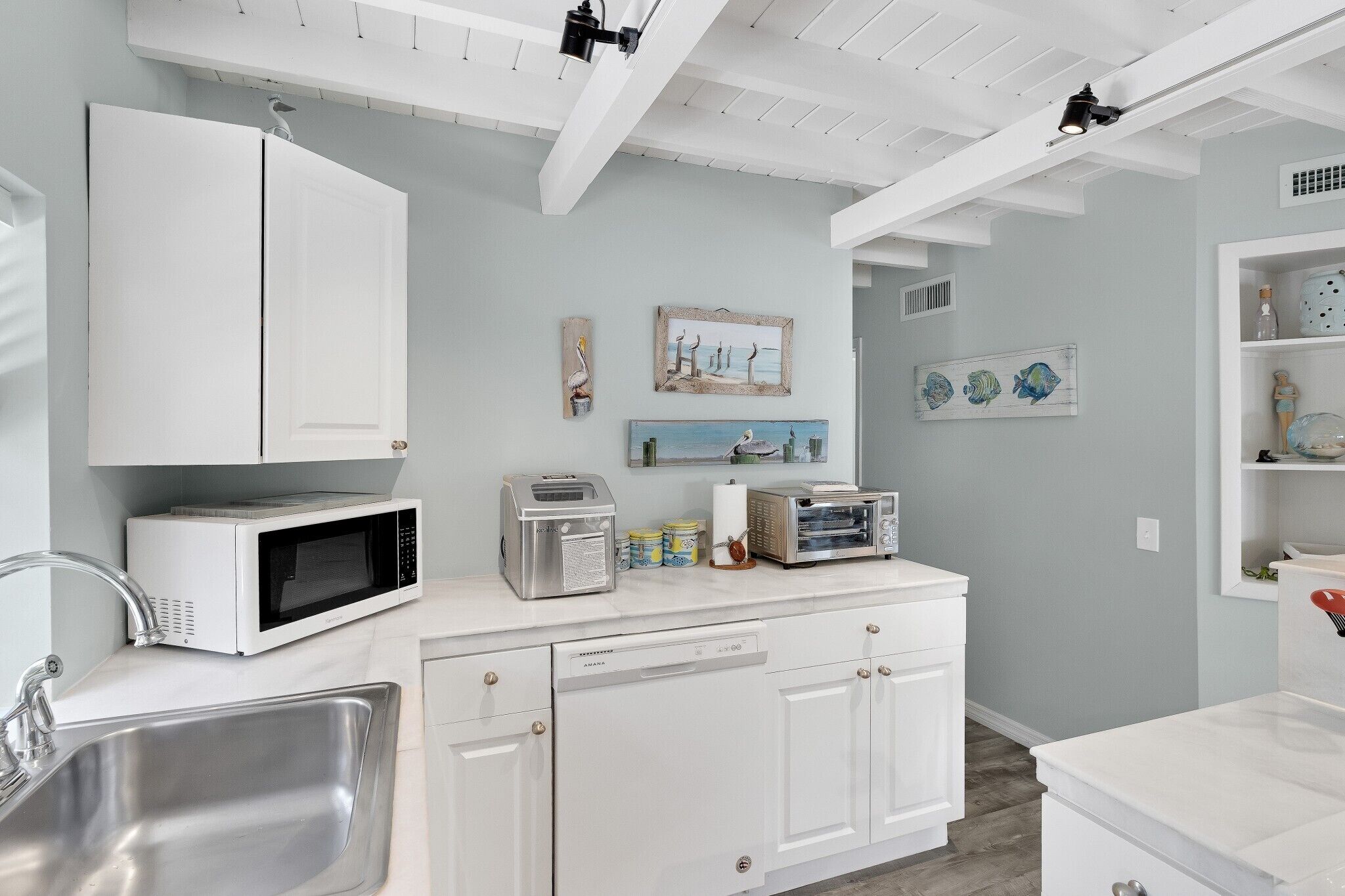A modern kitchen with white cabinetry, a built-in microwave, and a sink.