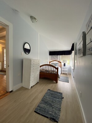 A bedroom with a wooden bed, a white dresser, a mirror, and a window with a dark valance. - Sunny Jenness Beach View Home – Quiet Rd, Perfect for Families & Coastal Escapes (Rye)