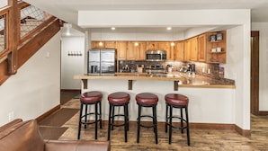 A modern kitchen with wooden cabinets, stainless steel appliances, and a central island with bar stools.