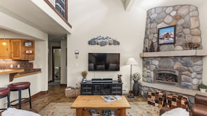 A cozy living room with a stone fireplace, a flat-screen TV, and comfortable seating.