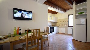 Une cuisine compacte avec un coin repas, un téléviseur fixé au mur et un réfrigérateur.