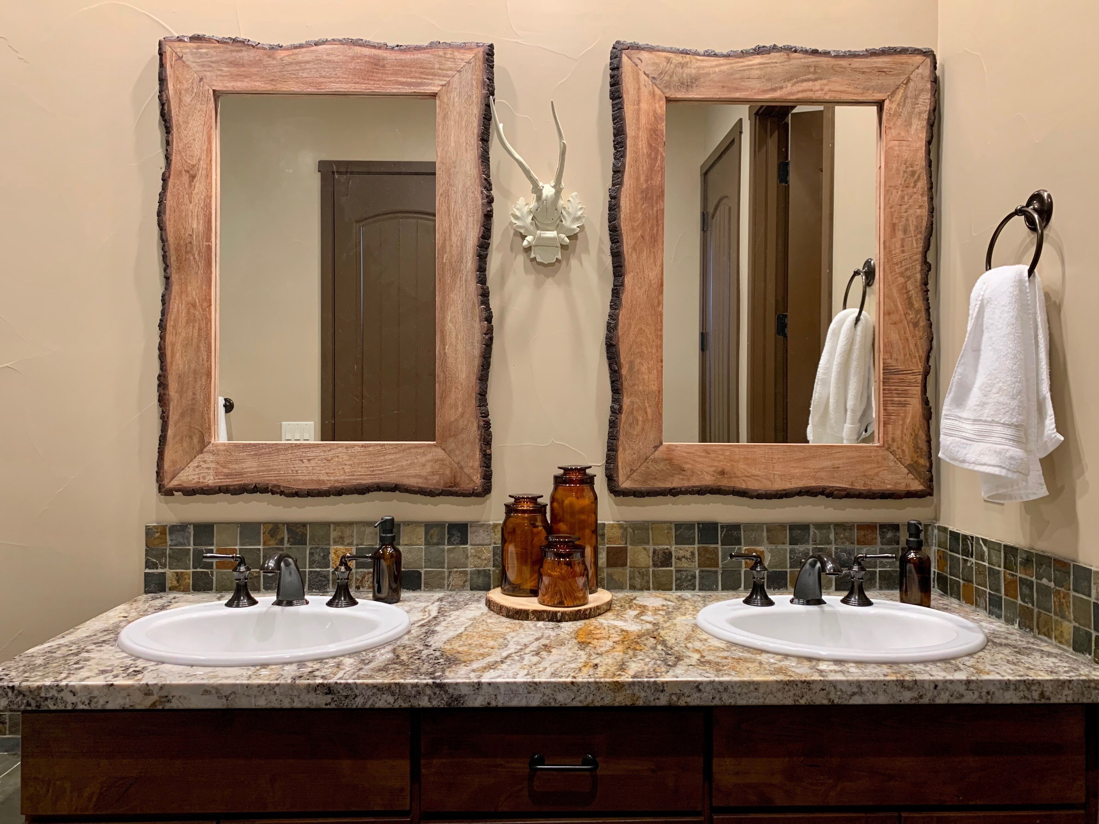 Une salle de bain avec deux lavabos, deux miroirs, un porte-serviettes et un élément décoratif mural.