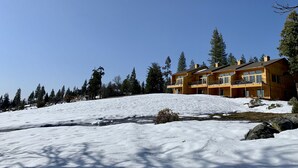 A large wooden building with multiple balconies, surrounded by snow-covered ground and tall pine trees. - The EDGE:  Picturesque & Secluded Gem - Scenic View (Shaver Lake)