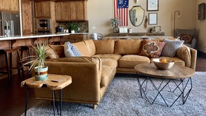 A spacious living room with a large brown sectional sofa, a wooden coffee table, and a small side table with a plant. - The EDGE:  Picturesque & Secluded Gem - Scenic View (Shaver Lake)