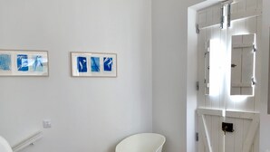 A room with a bed, a chair, a desk, and a door with a window.