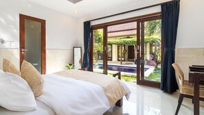 Quarto com uma cama grande, uma escrivaninha e vista para uma piscina e jardim.