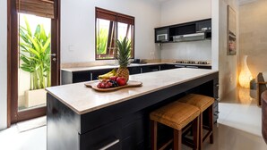 Uma cozinha moderna com ilha central, armários pretos, micro-ondas e uma cesta de frutas.