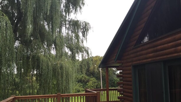 A wooden deck with a railing, a covered area with a roof, and a large window.