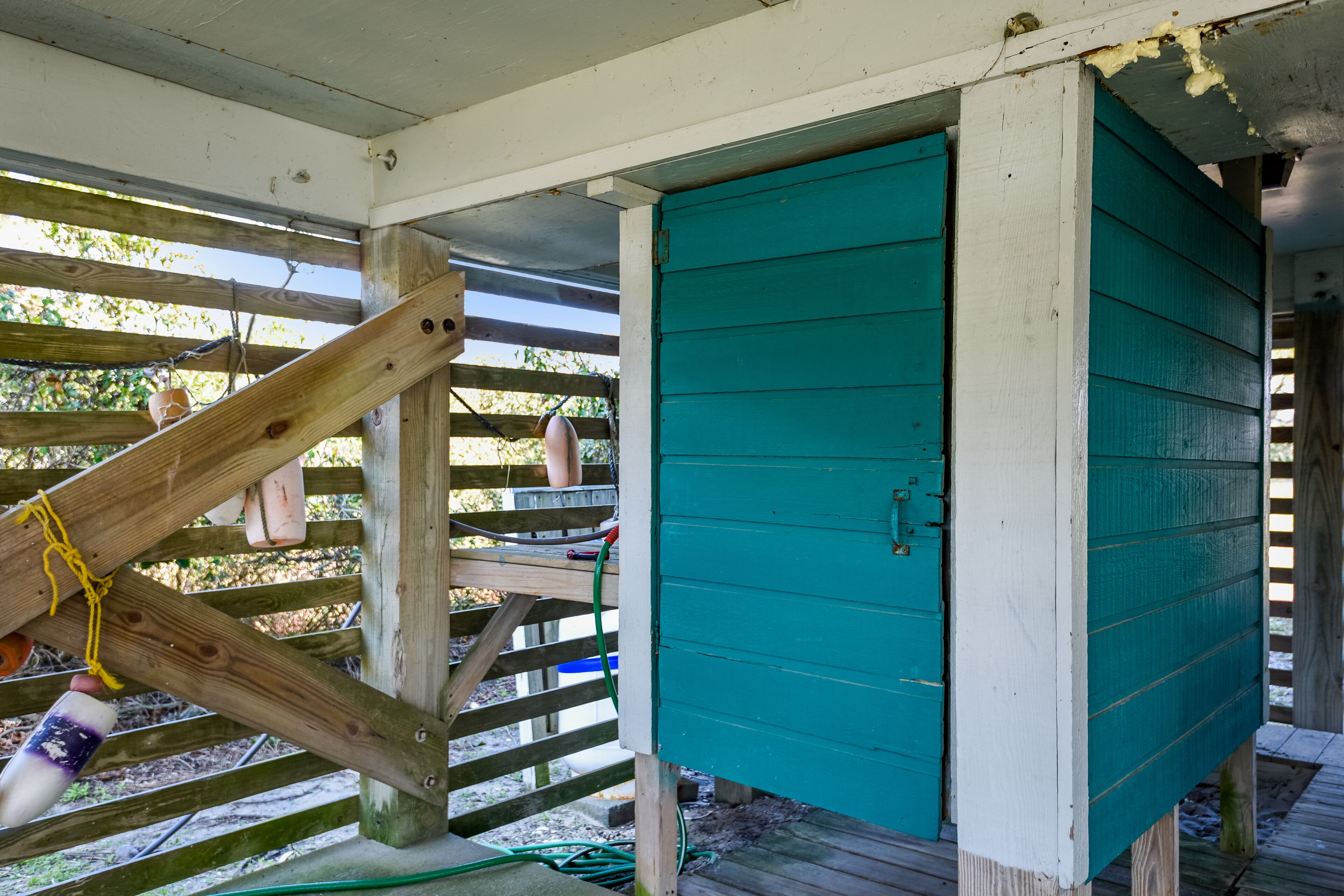 A wooden structure with a teal door, a wooden staircase, and a wooden fence.