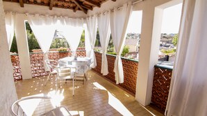 A sunlit balcony with a table and chairs, a view of the city, and a wooden ceiling. - Seaside cottage in residence (Costa Saracena)