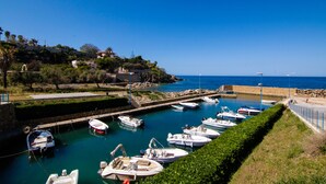 A marina with boats docked, a clear blue sky, and a hillside with buildings. - Seaside cottage in residence (Costa Saracena)