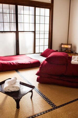 Una estança amb tatamis, un llit futó, una taula petita amb tovalloles i una làmpada japonesa tradicional.