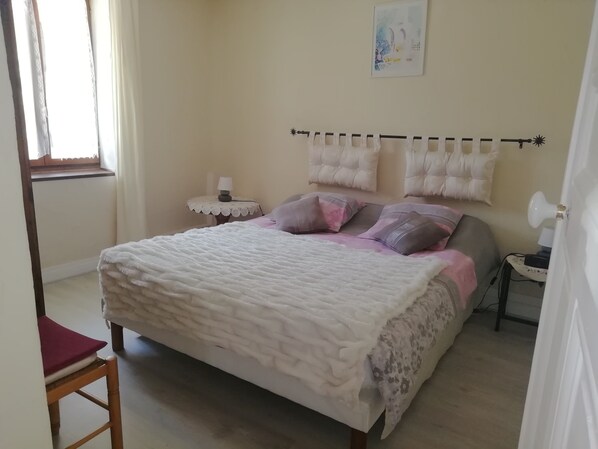 A bedroom with a bed, a bedside table, a chair, and a window.