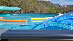 A pool with inflatable toys and a view of mountains in the background.