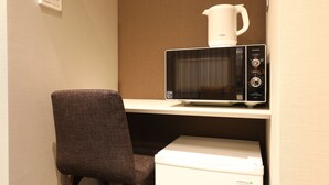 A microwave on a white countertop, a white coffee maker, and a white box labeled "HERB Relax" below the microwave. - Hotel Cocon (Fukuoka)