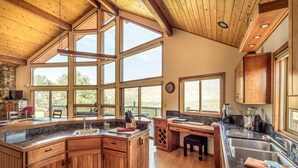 A spacious kitchen with wooden cabinets, a large island, and multiple windows offering views of the outdoors.