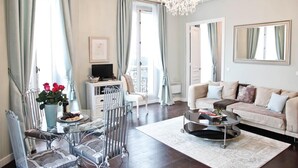 A spacious living room with a sofa, coffee table, and a glass dining table with chairs. - Perfectly Parisian, Bright & Elegant with Balcony (Paris)
