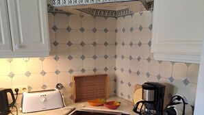 A kitchen with white cabinets, a stove, a toaster, a coffee maker, and a decorative tile backsplash.