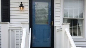 A front view of a house with a blue door, white railings, and a small porch. - Cape May Beautiful Condo(5minutes to the Beach) (Cape May)