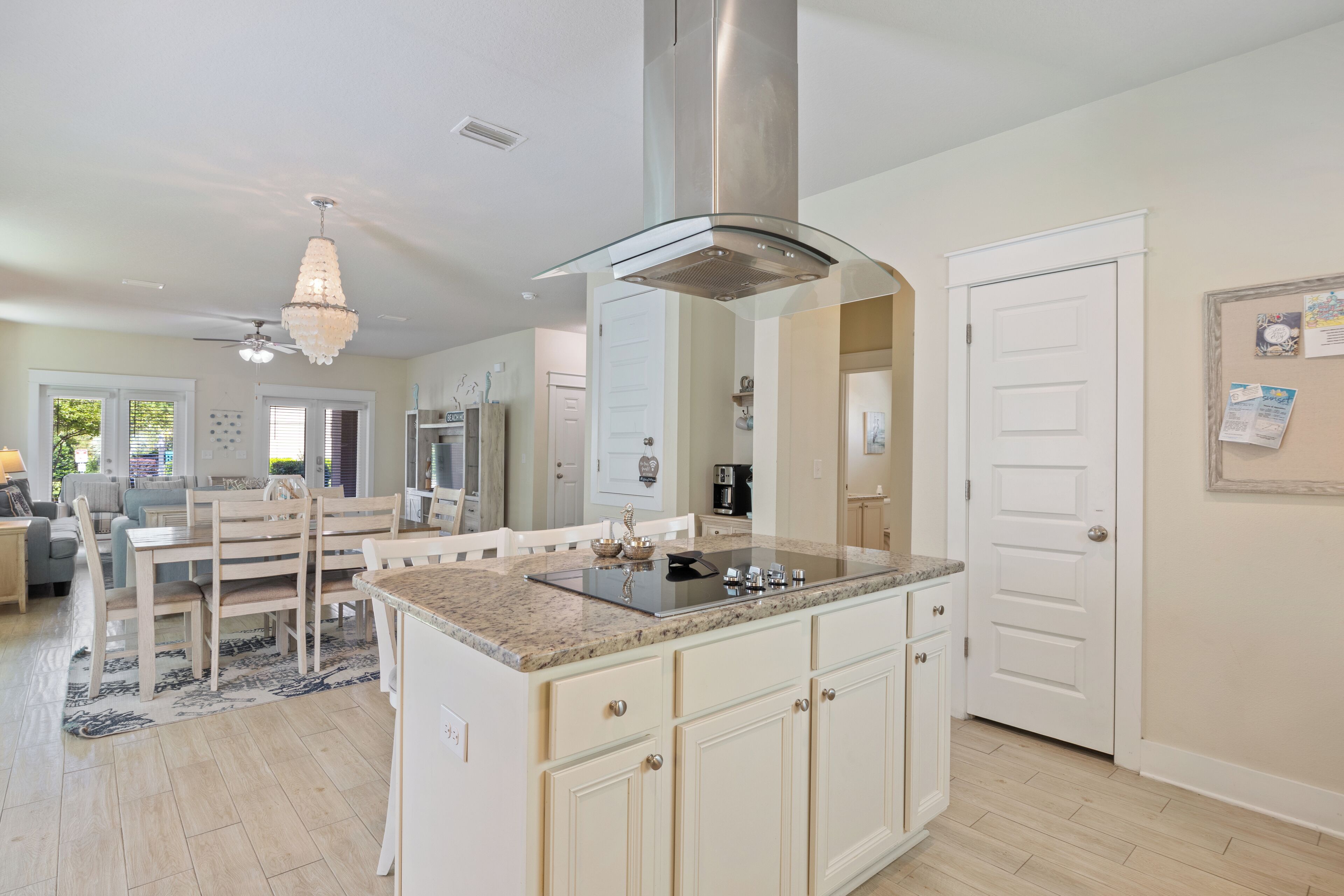 A modern kitchen with a central island, white cabinetry, and a stainless steel range hood.