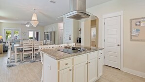 Una cocina moderna con una isla central, armarios blancos y una campana extractora de acero inoxidable.