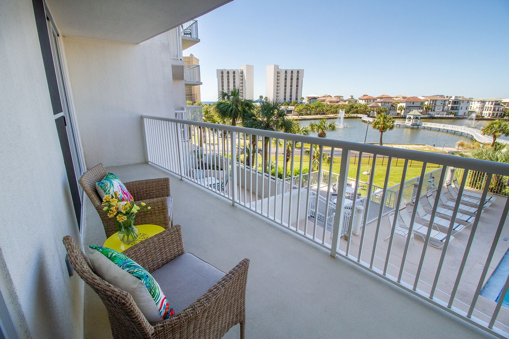 A balcony with wicker furniture, a small table, and a vase with flowers.