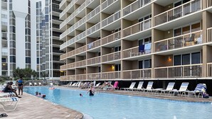 Et hotelområde med swimmingpool, flere niveauer af altaner og liggestole.