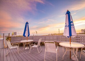 A deck with outdoor seating, including tables and chairs, and two umbrellas.