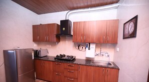 Eine Küche mit Holzausstattung, einem Edelstahl-Kühlschrank, einer Mikrowelle und einem Gasherd.