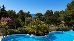 Una piscina a forma di curva con acqua cristallina e trasparente, circondata da vegetazione lussureggiante e alberi.