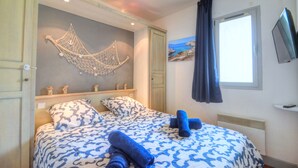 Una camera da letto con un letto, un pannello decorativo, un quadro e una televisione.