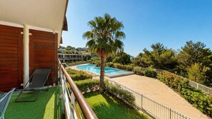 Un balcone con piscina, una palma e vista su una zona residenziale.