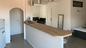 Uma cozinha moderna com ilha de madeira, luminárias pendentes e uma geladeira embutida.
