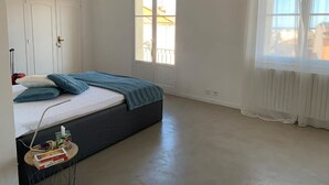 Quarto com uma cama, janela, radiador e porta.