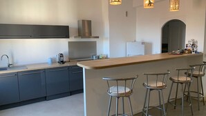 Uma cozinha moderna com uma ilha central, banquetas e iluminação pendente.
