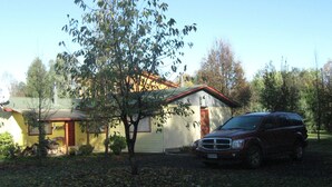 Una casa con garaje, un árbol en frente y un SUV estacionado.